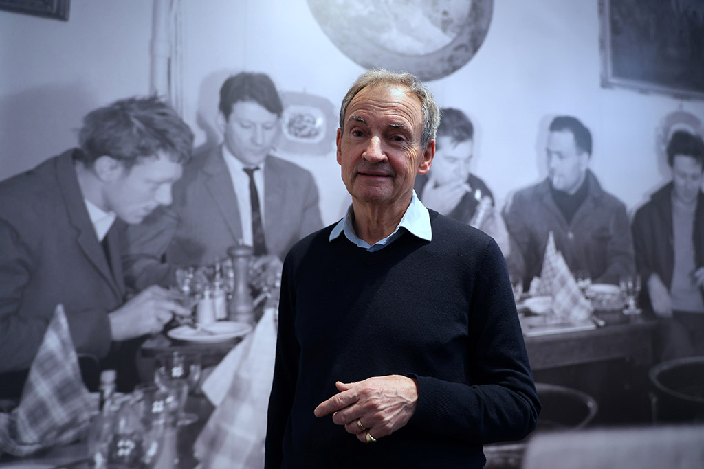 Curator Richard Calvocoressi poses in front of a picture by John Deakin of painters (from left to right) Timothy Behrens, Lucian Freud, Francis Bacon, Frank Auerbach and Michael Andrews at Wheelers Restaurant in London in 1963 displayed at the 
