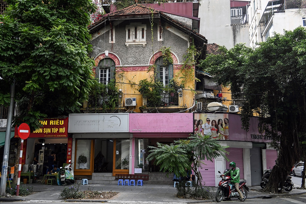 This photo shows a motorbike taxi driver waiting for customers in front of an old villa in Hanoi.