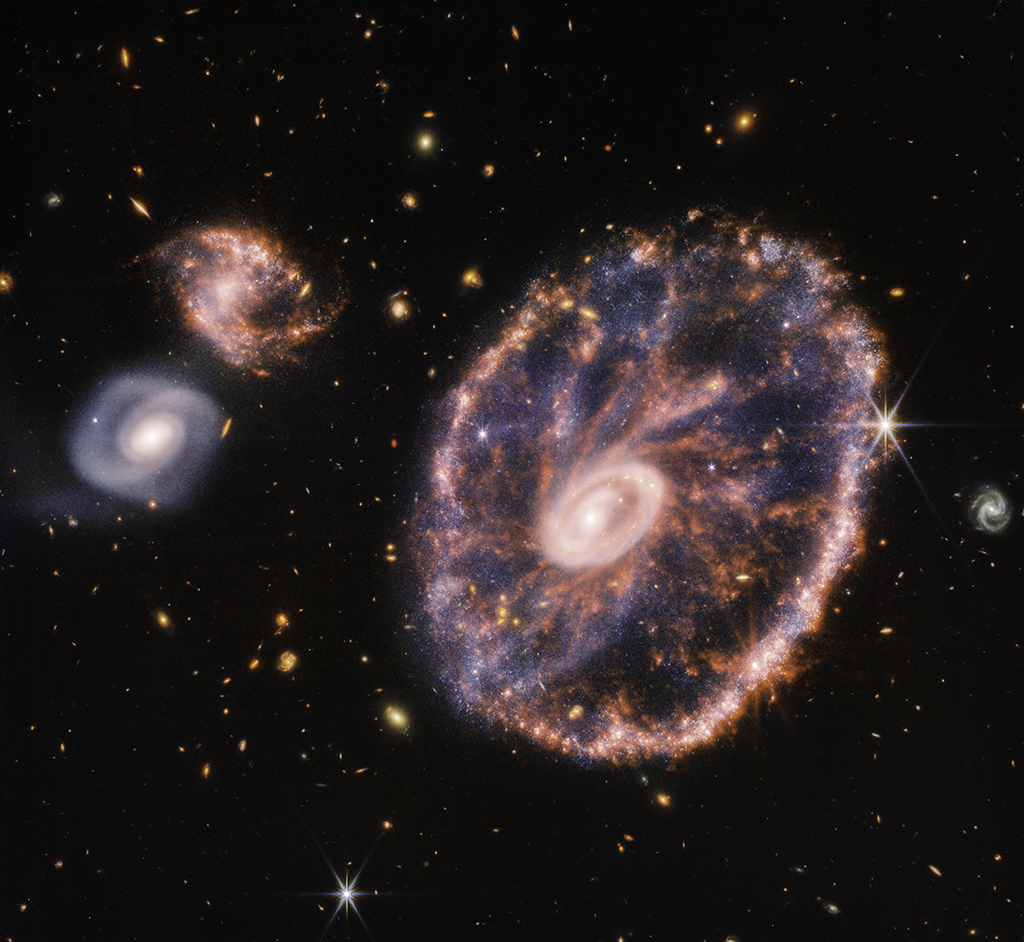 This handout composite image from Webb’s Near-Infrared Camera (NIRCam) and Mid-Infrared Instrument (MIRI) released by NASA shows the Cartwheel and its companion galaxies, revealing details that are difficult to see in the individual images alone.