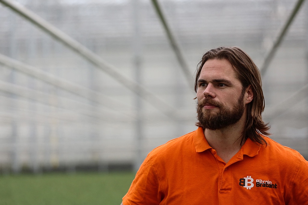 Bert De Groot, 35, bitcoin engineer and owner of Bitcoin Brabant, wears a t-shirt with the bitcoin logo among tulips in the greenhouse.