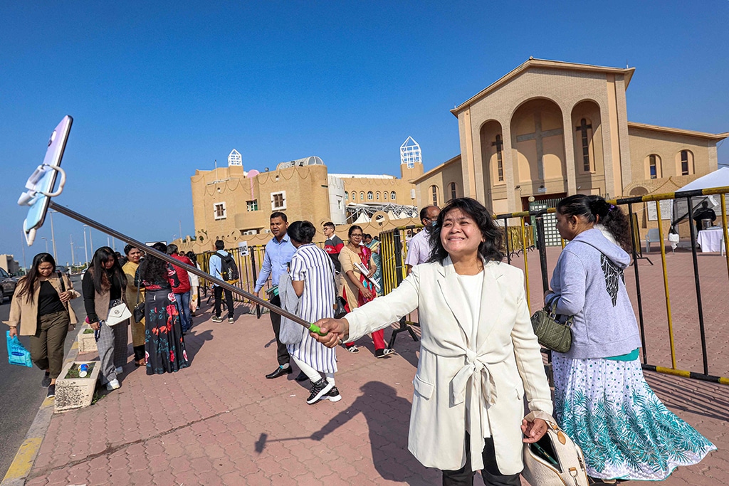 A woman uses a phone on a ‘selfie stick’ to take a photo outside the Catholic Cathedral in Kuwait City on Christmas Day on December 25, 2022.