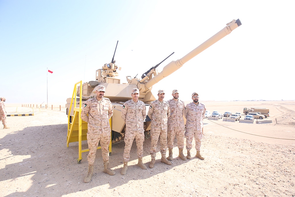 KUWAIT: Military personnel pose for a picture in front of a military tank.