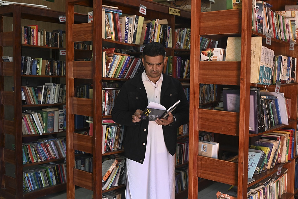 A former arms dealer and founder of Darra Adam Khel Library, Raj Muhammad looks at a book inside the library in Darra Adamkhel town.