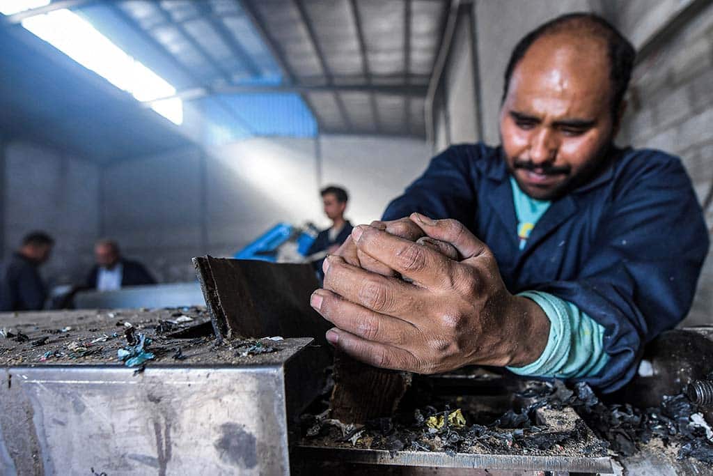 A worker shreds plastic waste to be recycled into eco-friendly interlocking tiles used in outdoor walkways at a workshop of the startup company 