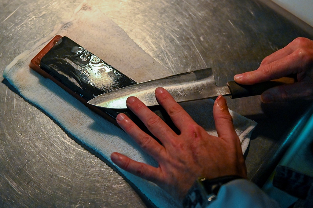 French chef Olivier Oddos, whose Tokyo restaurant boasted a Michelin star between 2014 and 2021, cleaning a knife with whetstone at his restaurant's kitchen in Tokyo.