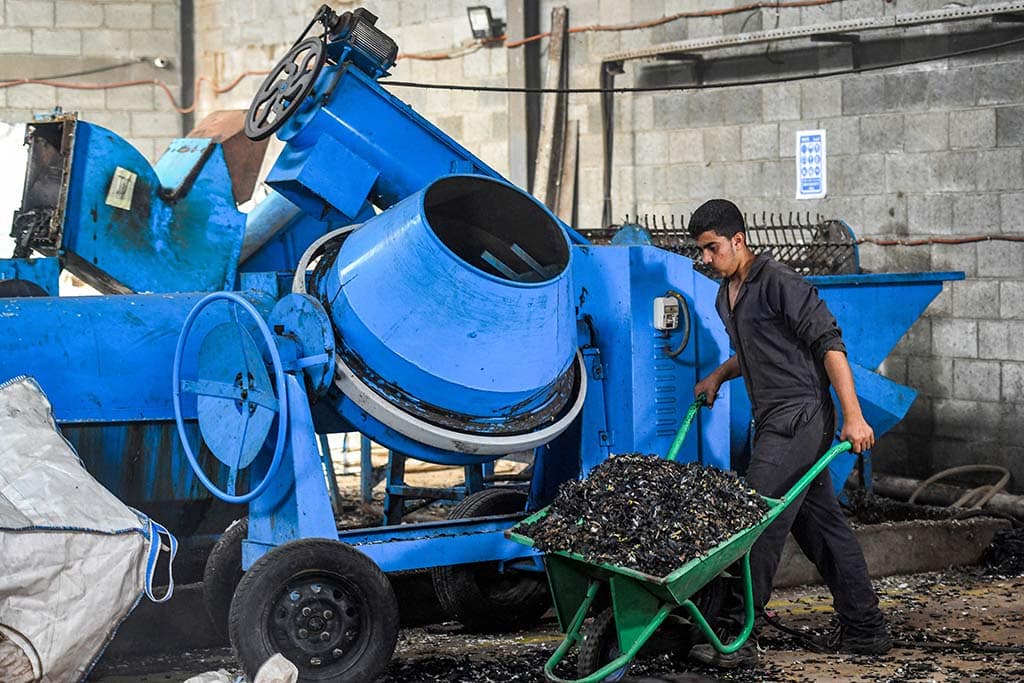 A worker dumps plastic waste out of a mixer before it is to be recycled into eco-friendly interlocking tiles.