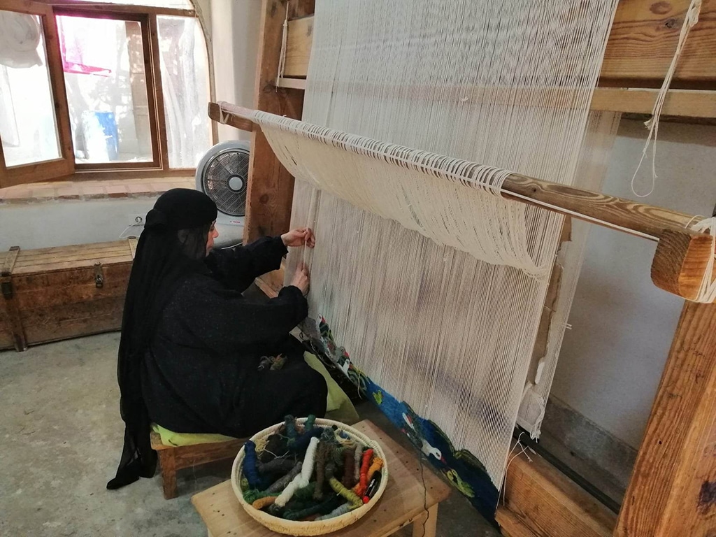An artist finishing up her weaved textile.