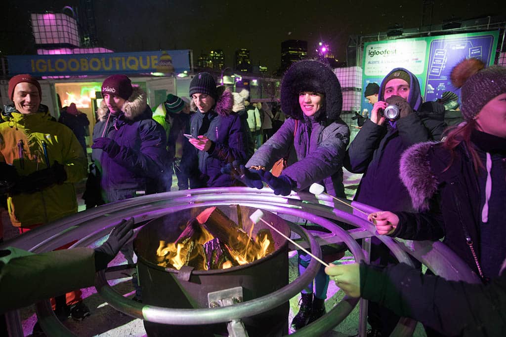 Fans warm their hands and roast marshmallows during Igloofest 2023 in Montreal.