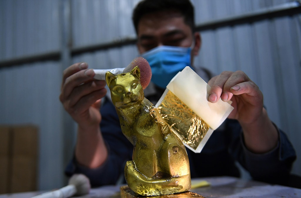 This photograph shows man gilding a cat figurine at a factory in Hanoi, ahead of the lunar new year.