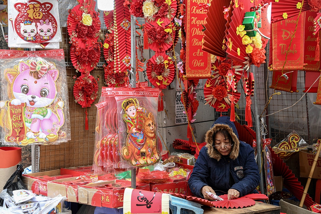 This photograph shows a shopkeeper at a stall that is selling cat images ahead of the lunar new year at a market in the old quarters of Hanoi.