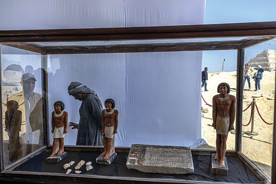 Workers stand behind a collection of pharaoh statues during a press conference at the Saqqara archaeological site.