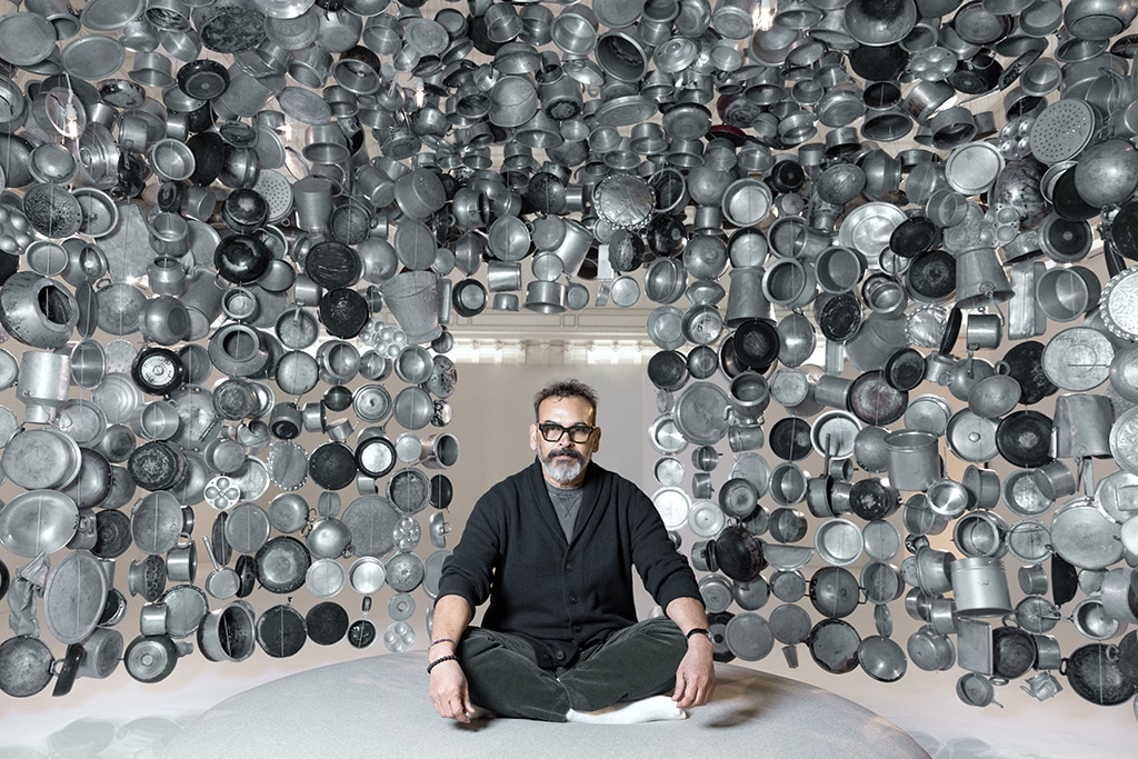 Indian artist Subodh Gupta poses in one of his installations, a hanging hut made with cooking pots collected from markets during his exhibition entitled