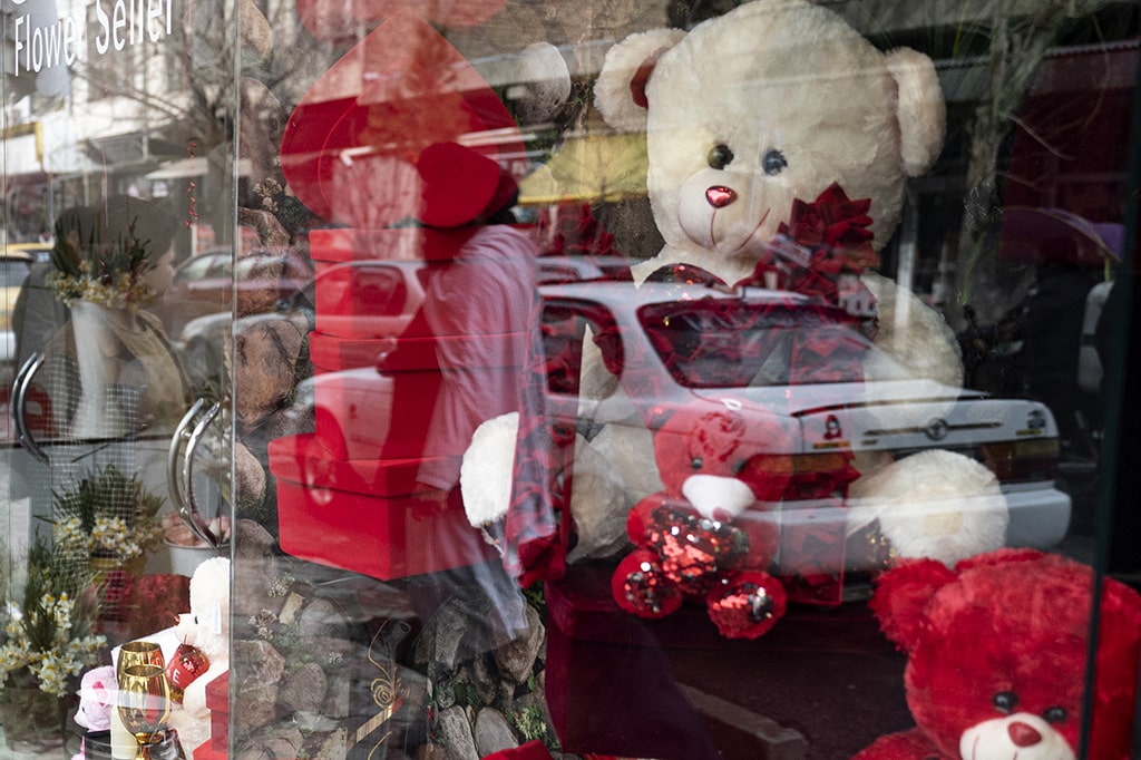 Afghan men are reflected on the glass of a gift shop along the flower street on the occasion of Valentine's Day in the Shar-e-Naw area of Kabul. 