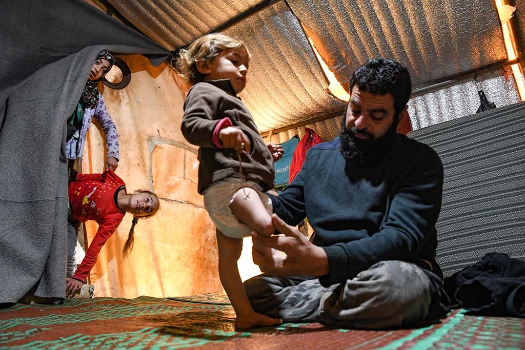 IDLIB: Mohammed, the father of Syrian Maya Merhi, sits  next to his disabled toddler, inside the family tent at an  Internally Displaced Persons (IDP) camp in Syria’s rebelheld northwestern Idlib province. — AFP