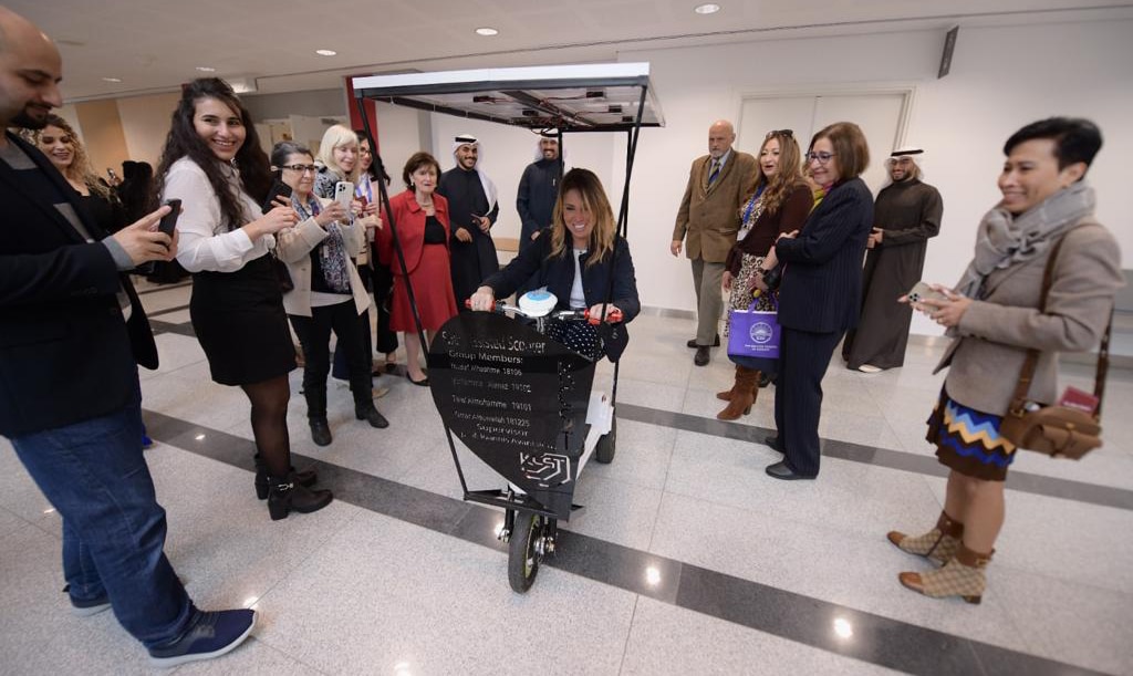 Ghada Shawky, president of the IWG, tries the solar scooter invented by KCST students.