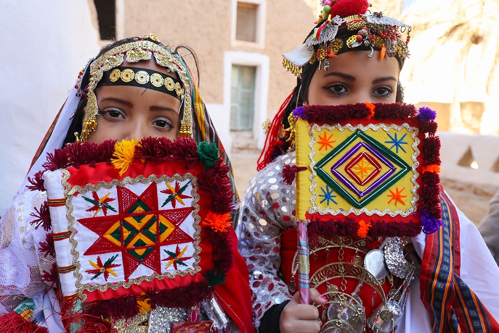 Young girls in colorful dress and traditional jewelry pose for a picture.
