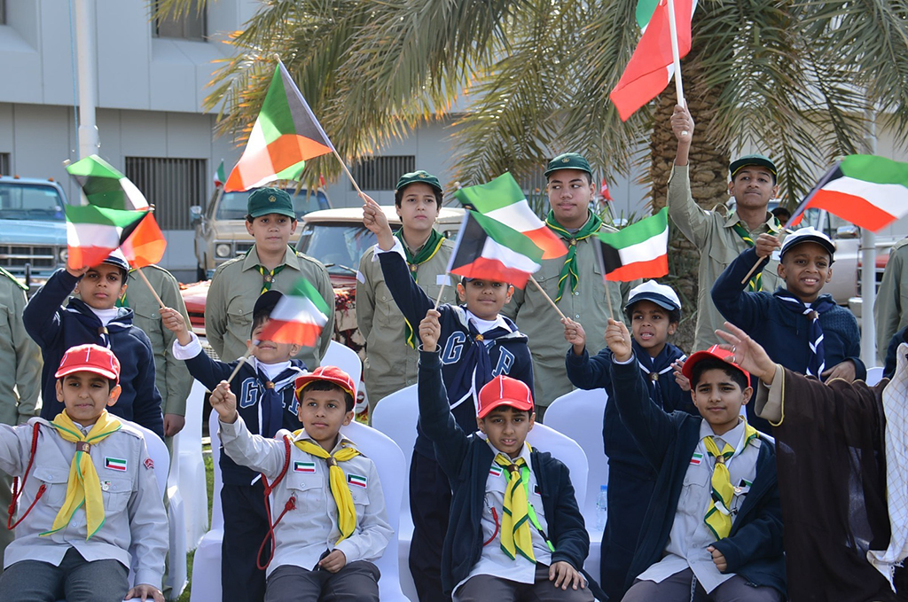 Children wave flags on the occasion during the celebrations at Ahmadi governorate.