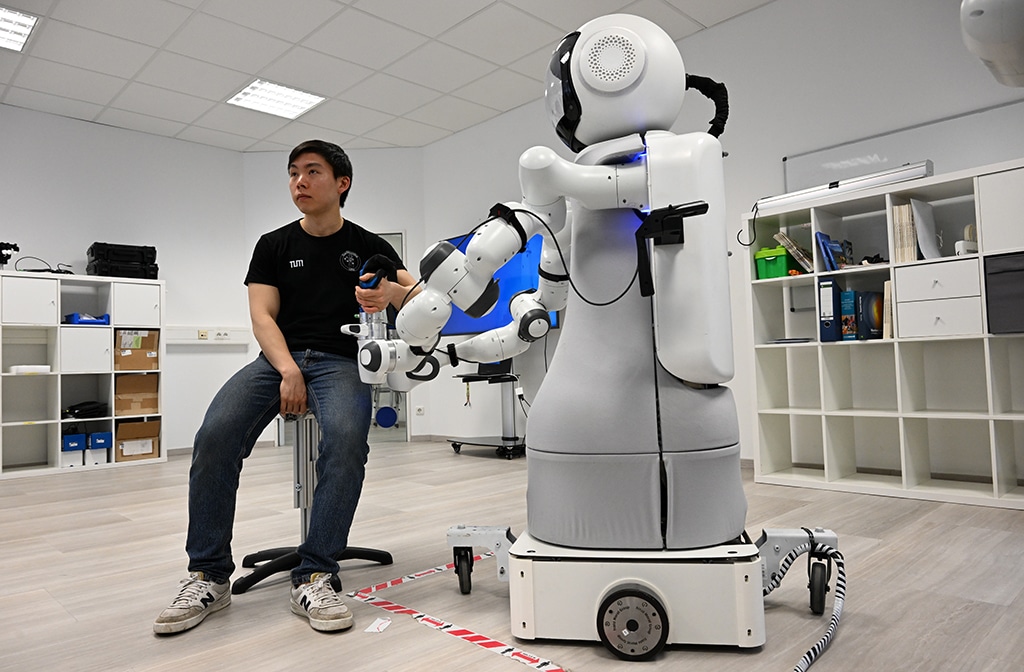 An employee sits in front of the robot Garmi.