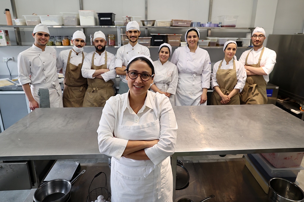 Iranian pastry chef Shahrzad Shokouhivand, poses for a picture with members of her team in the kitchen of her luxury pastry company in Tehran.