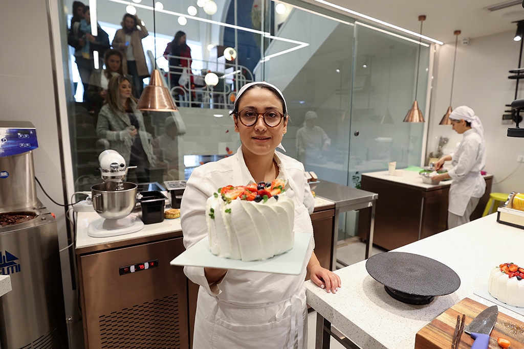 Iranian pastry chef Shahrzad Shokouhivand, poses for a picture with a cake in the kitchen of her luxury pastry shop in Tehran.