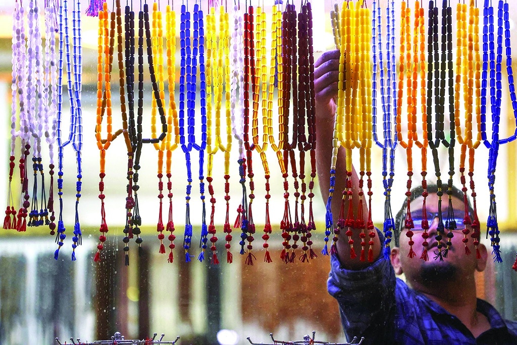A vendor sorts displayed prayer beads at a market.