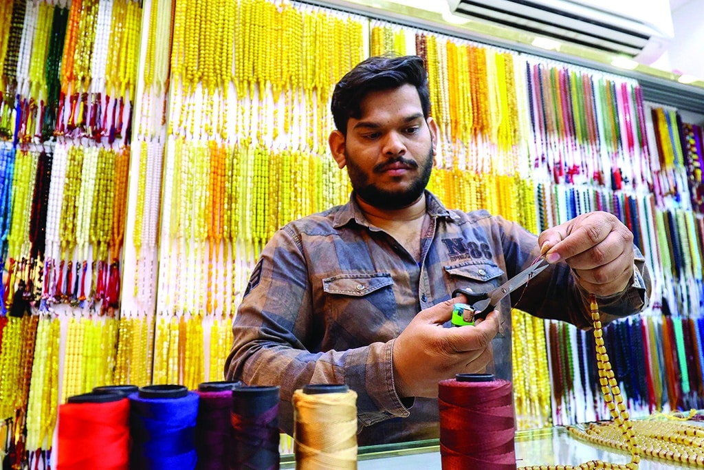 A vendor assembles prayer beads.
