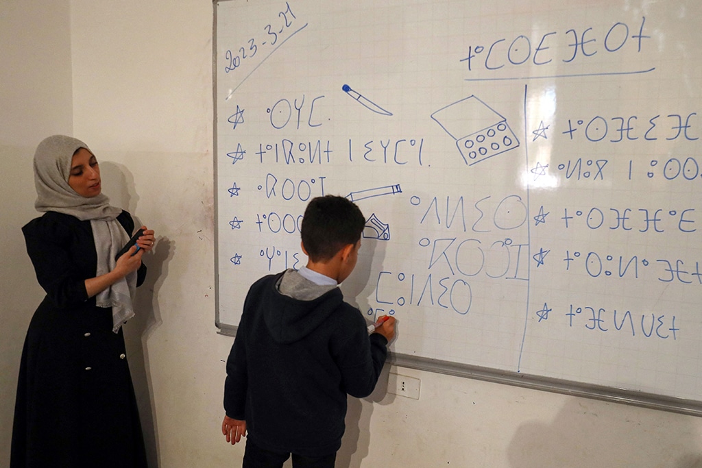In this picture teacher Assirem Shuwashia (left) watches as a Libyan pupil writes Tamazight language at a school in Zuwara, a majority-Berber community near the border with Tunisia.