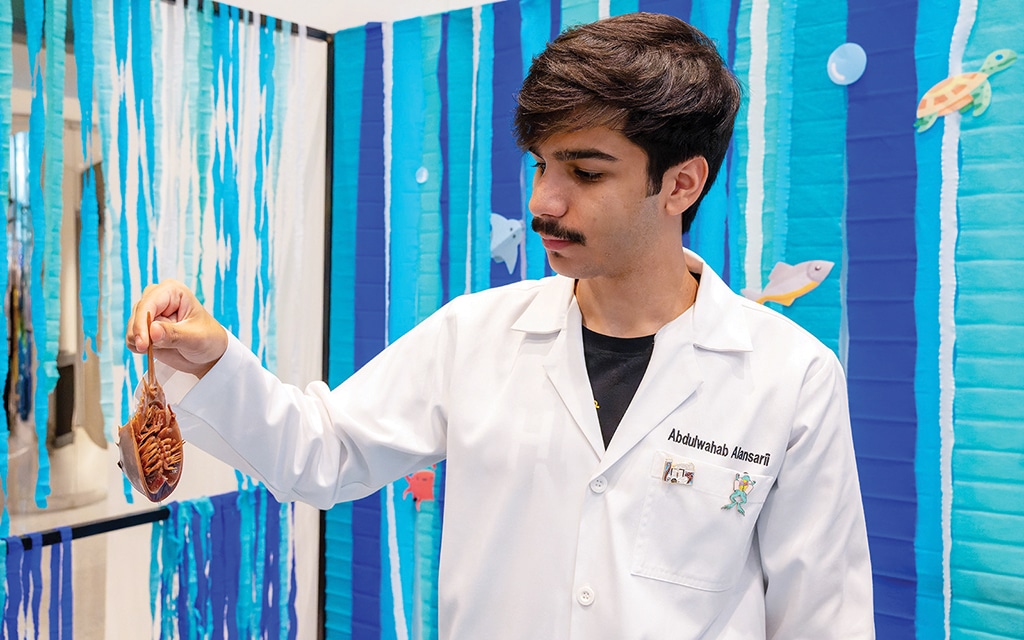 A marine sciences student shows visitors a specimen at the exhibit. — KUNA photos