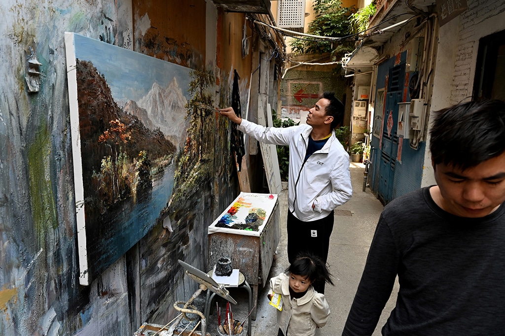 An artist paints in an alley at Dafen village.