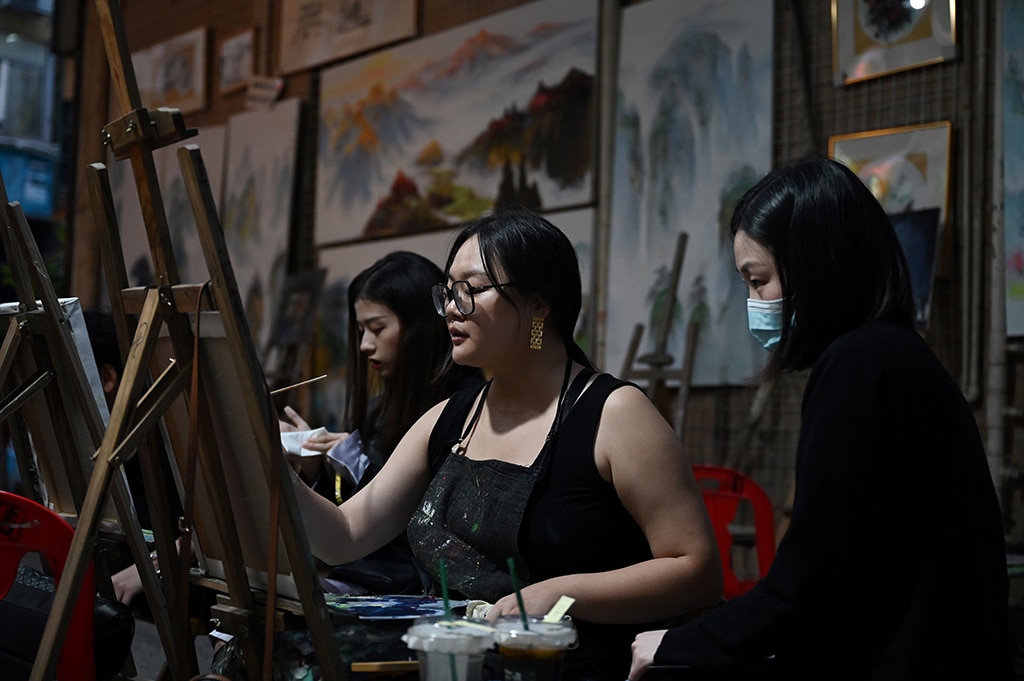 This picture shows people practicing painting in an alley at Dafen village.