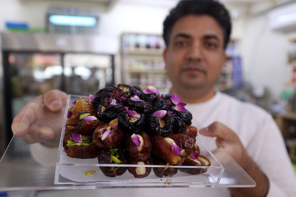 A vendor shows a box of dates stuffed with nuts and other ingredients at a shop in Kuwait City on April 1, 2023.