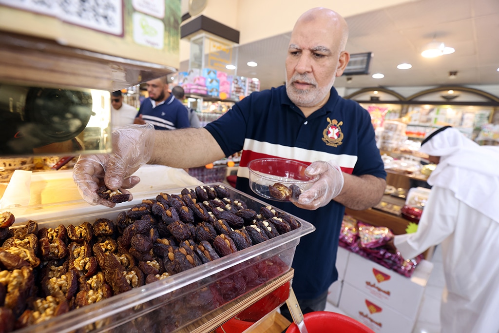 A vendor arranges dates stuffed with nuts and other ingredients at a shop in Kuwait City on April 1, 2023.