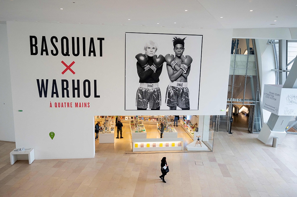 A visitor walks past a black and white photograph made in 1985 by US Michael Halsband, depicting portraits of US Neo-expressionism artist Jean-Michel Basquiat (right) (1960-1988) and US artist, film director and producer Andy Warhol (left) (1928-1987), during a preview of the exhibition “Basquiat X Warhol”.