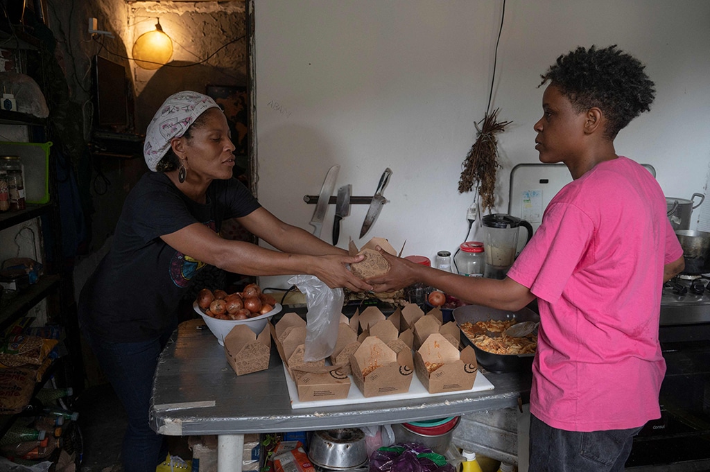 Brazilian chef Ana Lucia Costa (right) gives a meal to one of her volunteers at the Rocinha favela in Rio de Janeiro.