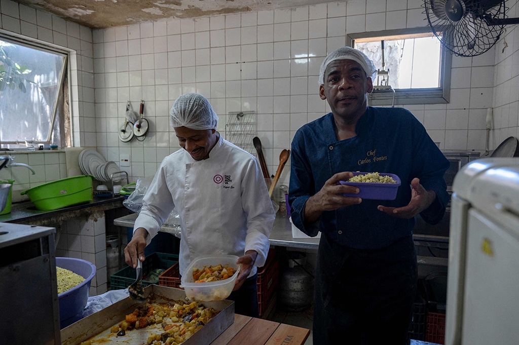 Brazilian chef Carlos Alberto da Silva (R), known as Nego Breu, gestures while cooking food to be delivered to the homeless population of the city center of Rio de Janeiro.