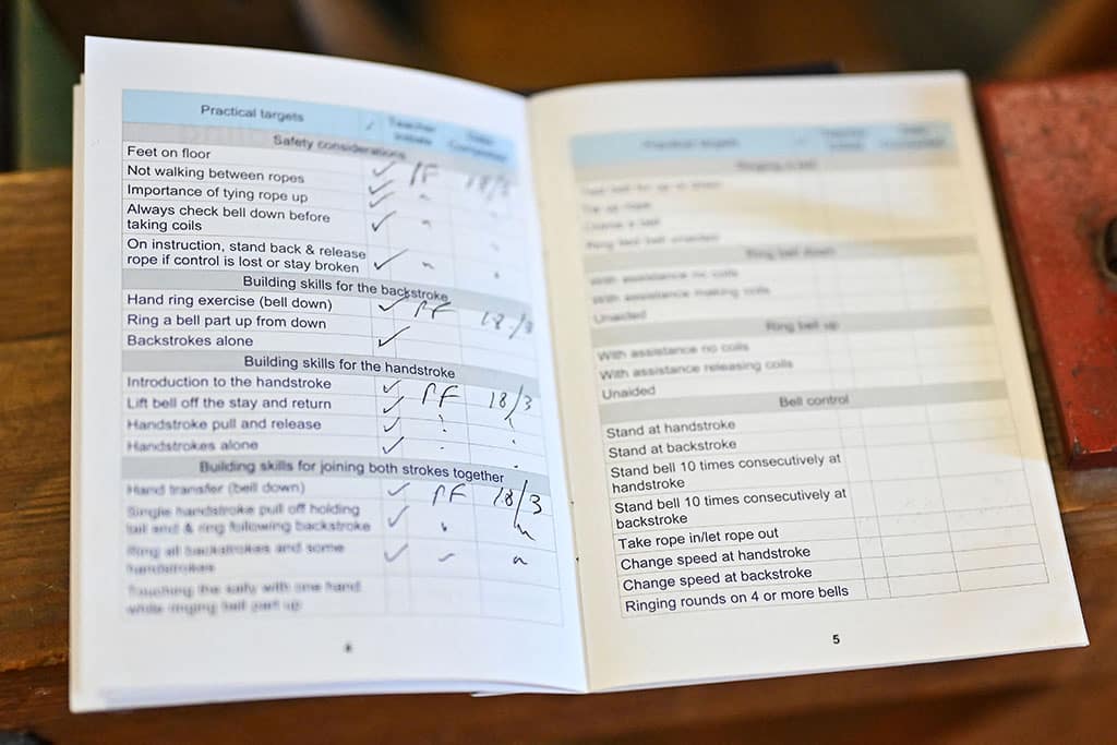 A photograph shows a training book which lists practical targets during a bell ringing training session at All Saints Church, Kingston-upon-Thames in southwest London.
