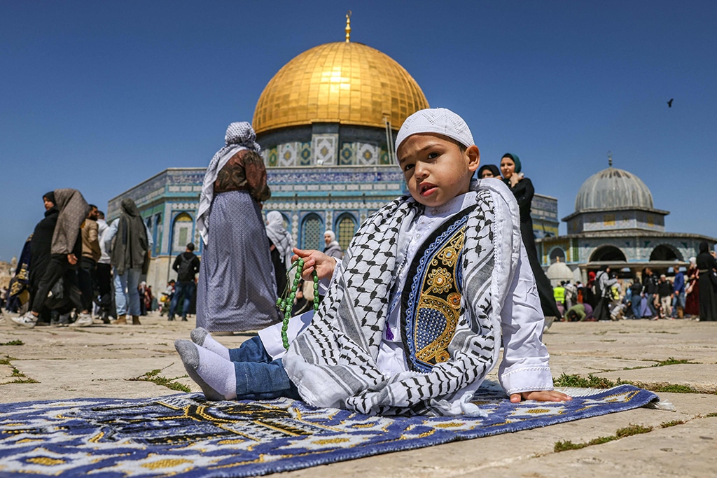 A young Palestinian Muslim worshipper sits with a prayer bead on a prayer mat ahead of the fourth Friday Noon prayers of the holy fasting month of Ramadan outside the Dome of the Rock mosque at the Al-Aqsa mosque compound, Islam’s third holiest site, in the Old City of Jerusalem.