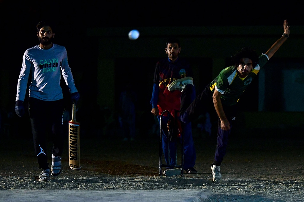 Cricketer Owais Afridi (right) delivers a ball during the tape ball night cricket tournament.