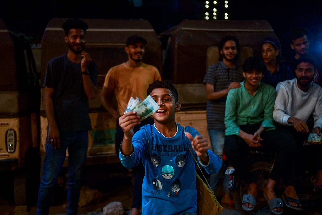A young supporter of the winning team hold prize money after the tape ball night cricket tournament.