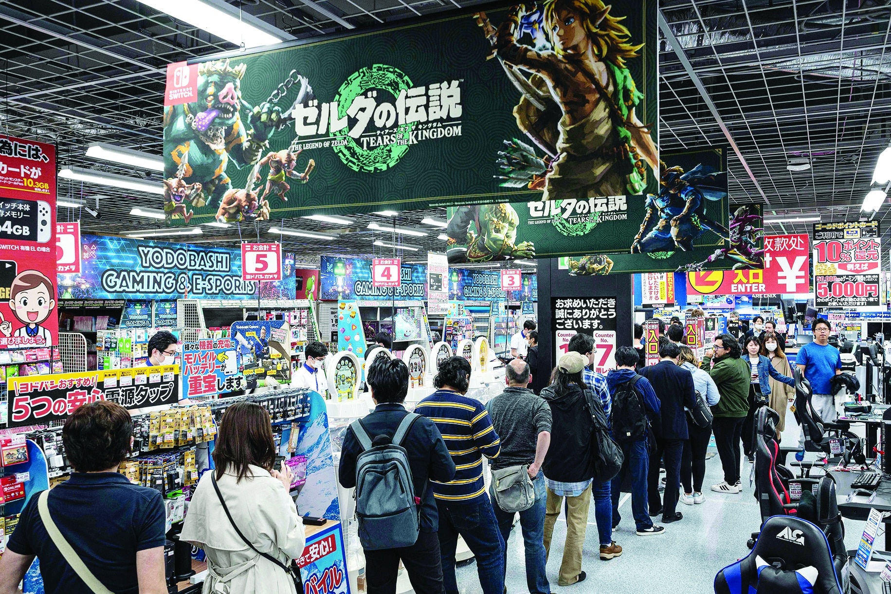 People queue up at the check-out counter as dozens of shoppers arrived early at a popular electronics chain store for the latest offering from Japanese gaming giant Nintendo's long-running 'Legend of Zelda' game series - 'Tears of the Kingdom' .