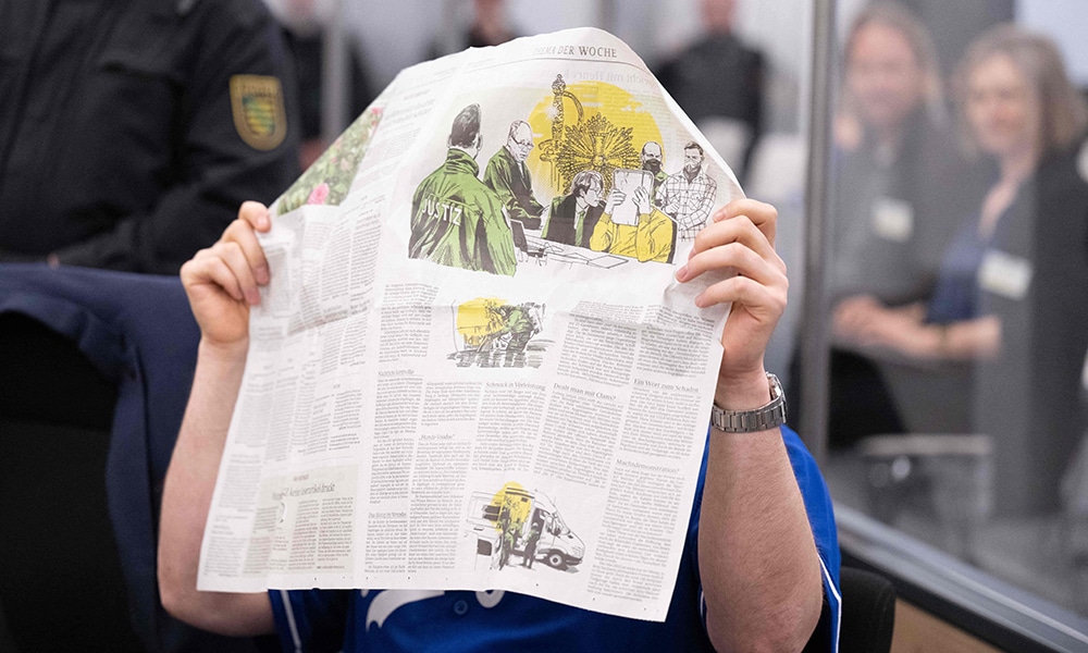 A defendant hides his face behind a newspaper reporting on his trial at the Higher Regional Court in Dresden, eastern Germany, prior to a hearing in the trial over a jewellery heist on the Green Vault (Gruenes Gewoelbe) museum in Dresden's Royal Palace in November 2019.