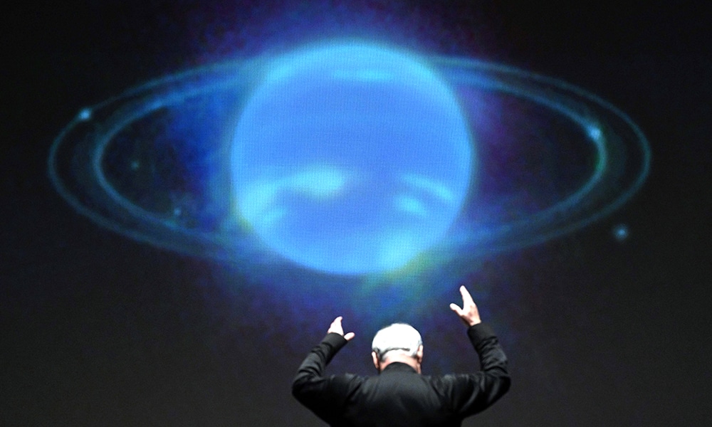 In front of an NASA image projected on a screen, National Philharmonic Music Director and Conductor Piotr Gajewski rehearses 'Cosmic Cycles, A Space Symphony' by composer Henry Dehlinger, at Capital One Hall in Arlington, Virginia.