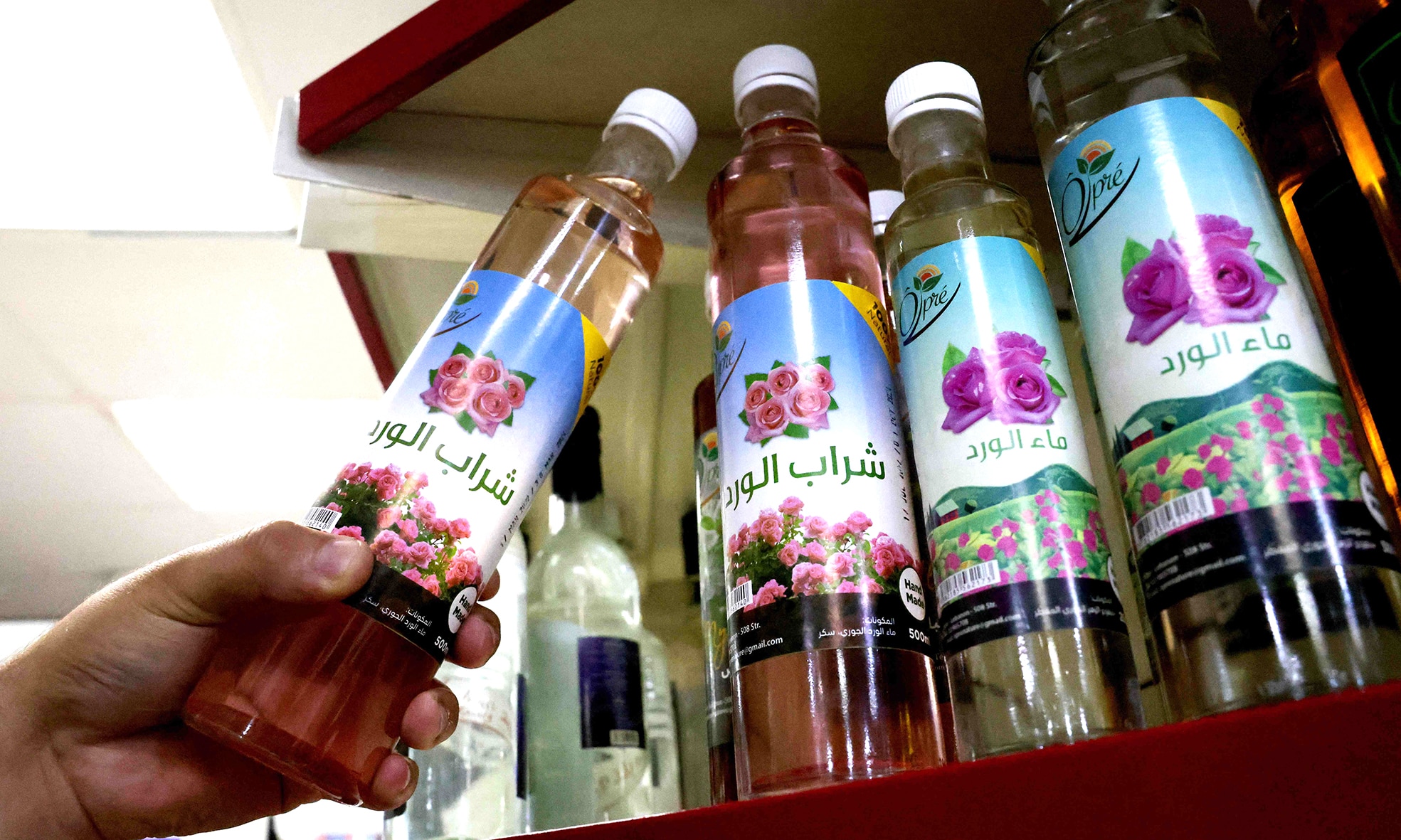 A man picks a bottle of Damascena (Damask)rose water at a shop in Byblos.