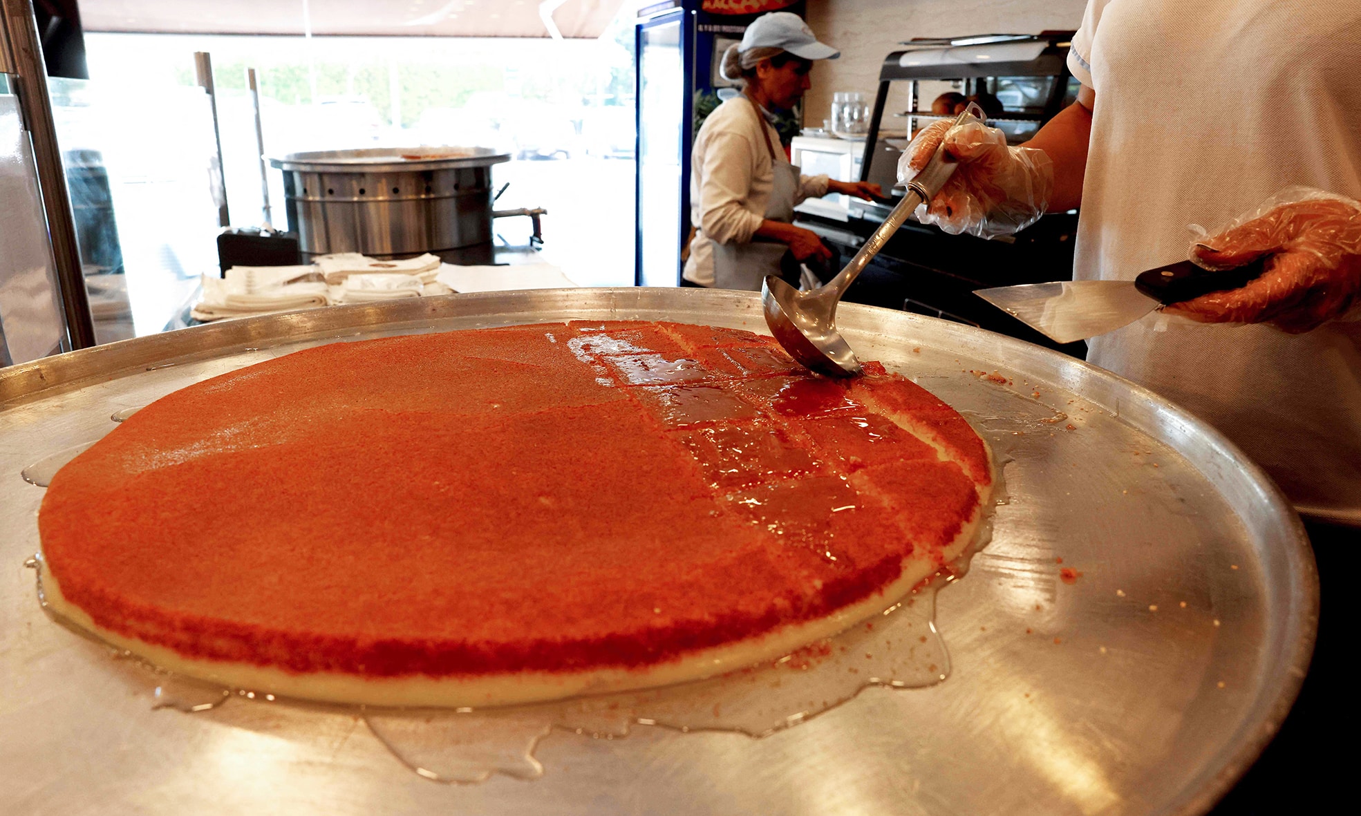 A workers pours syrup on a tray of traditional dessert Kunafa, at a shop in Byblos.