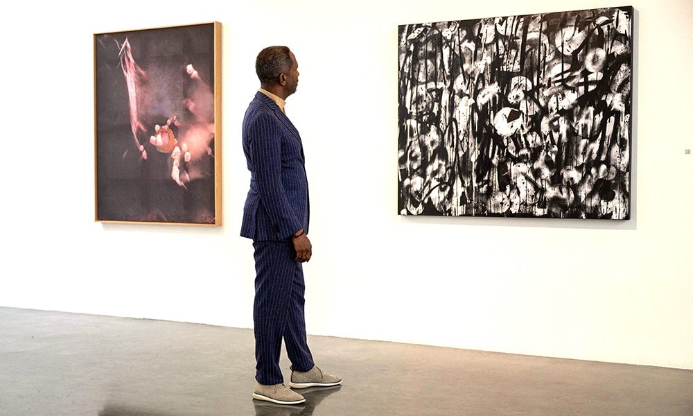 Brent Leggs, Executive Director of the African American Cultural Heritage Action Fund, looks at Anicka Yi's 'The Mother Tongue' (left and Adam Pendleton's 'Untitled (Days for Nina)' (right) displayed as part of the Nina Simone Childhood Home Auction Exhibition.