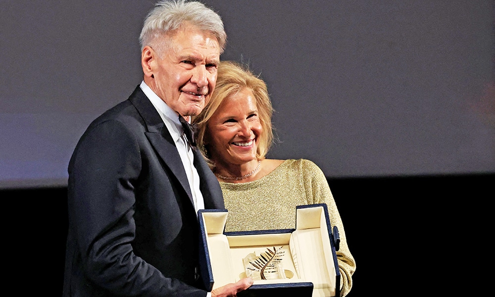 US actor Harrison Ford (left) poses on stage with French Director of the Cannes film festival Iris Knobloch after he was awarded with an Honourary Palme d'or prior to the screening of the film 'Indiana Jones and the Dial of Destiny”.