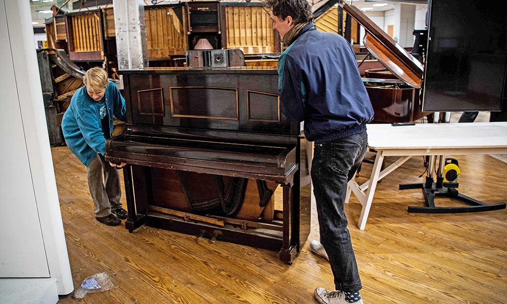 Volunteers push a piano at the Painodrome.