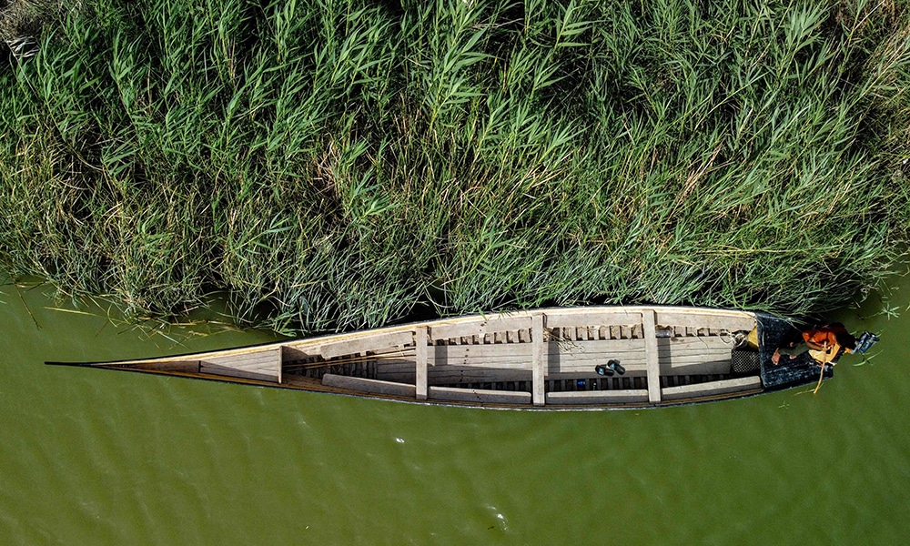 This aerial view shows a man rowing a newly-constructed traditional 'meshhouf' wooden boat in the area of al-Huwair in the sub-district of al-Madinah in Iraq's southern Basra province.