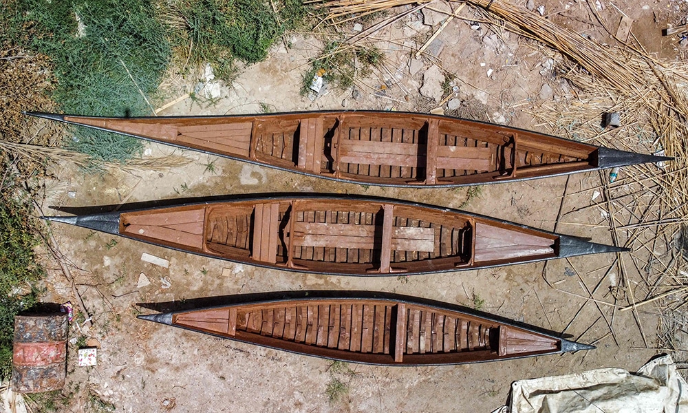 This aerial view shows traditional traditional 'meshhouf' wooden boats lying on the ground outside a workshop.