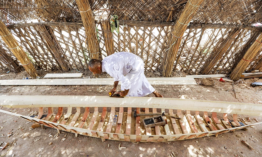 A carpenter shaves wood as he builds a traditional 'meshhouf' wooden boat at a workshop.